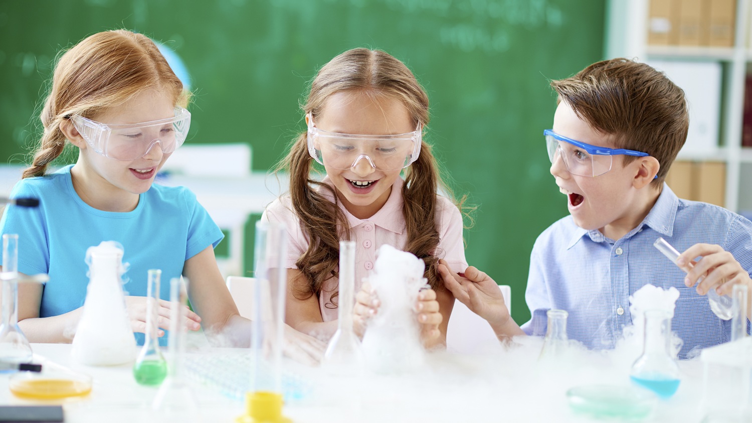 Three kids looking surprised and excited while doing a science experiment.